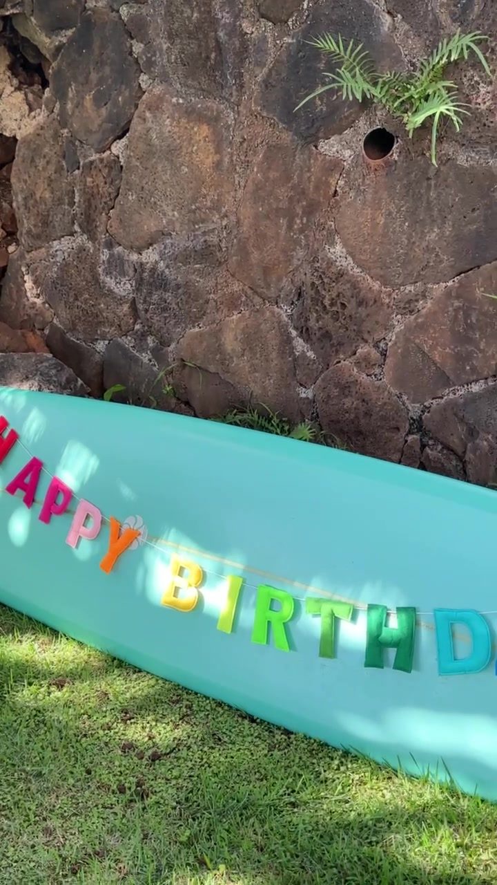 Teal surfboard sign reading Happy Birthday on the lawn