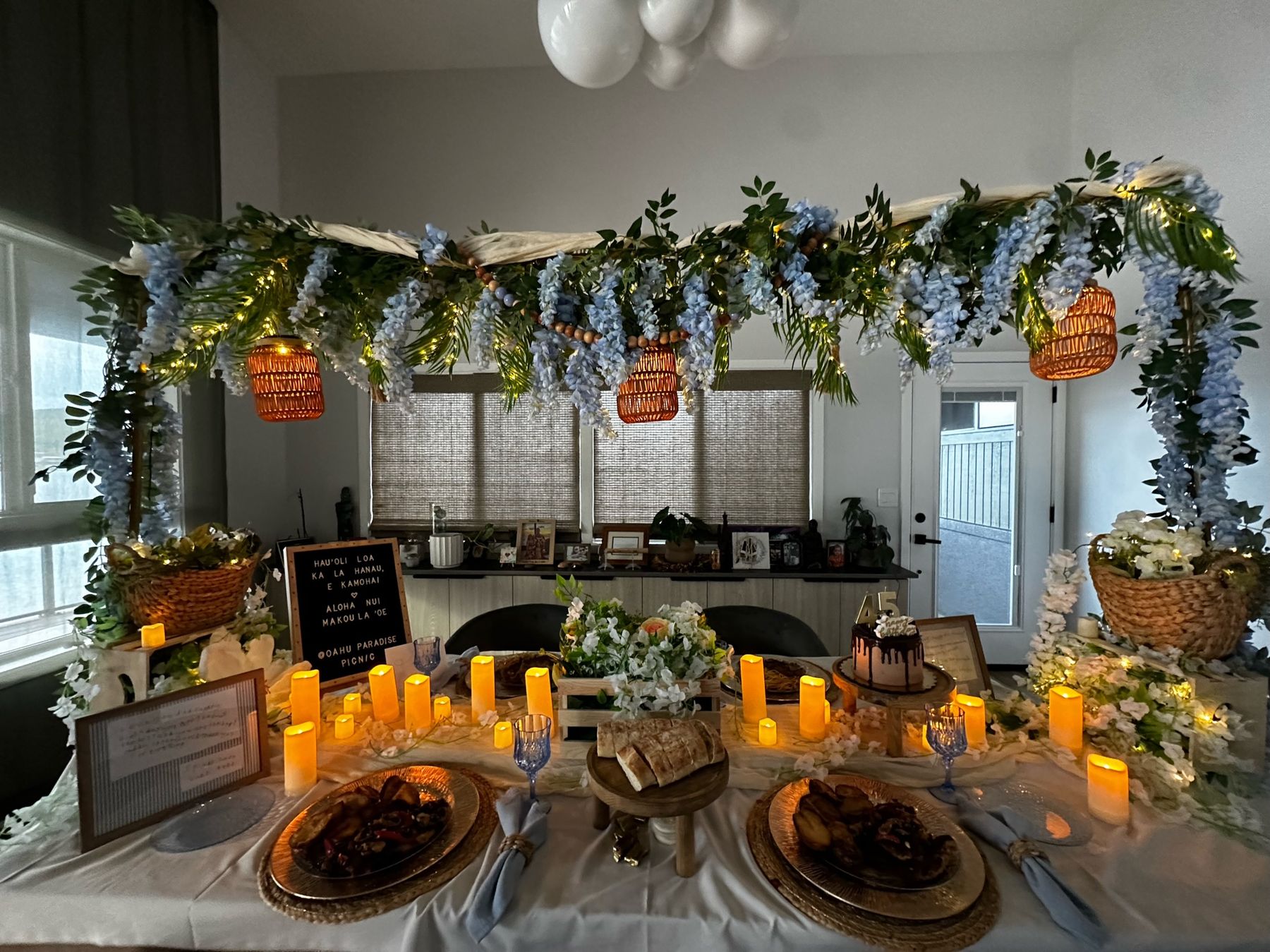 Wide view of the dinner table glowing with candles under the floral canopy