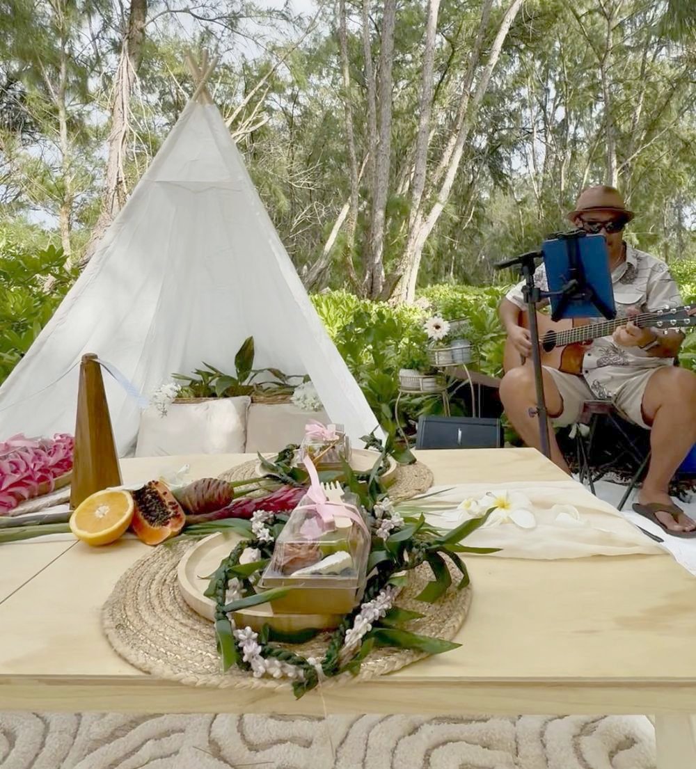 Live ukulele player beside the teepee and a place setting with an orchid lei