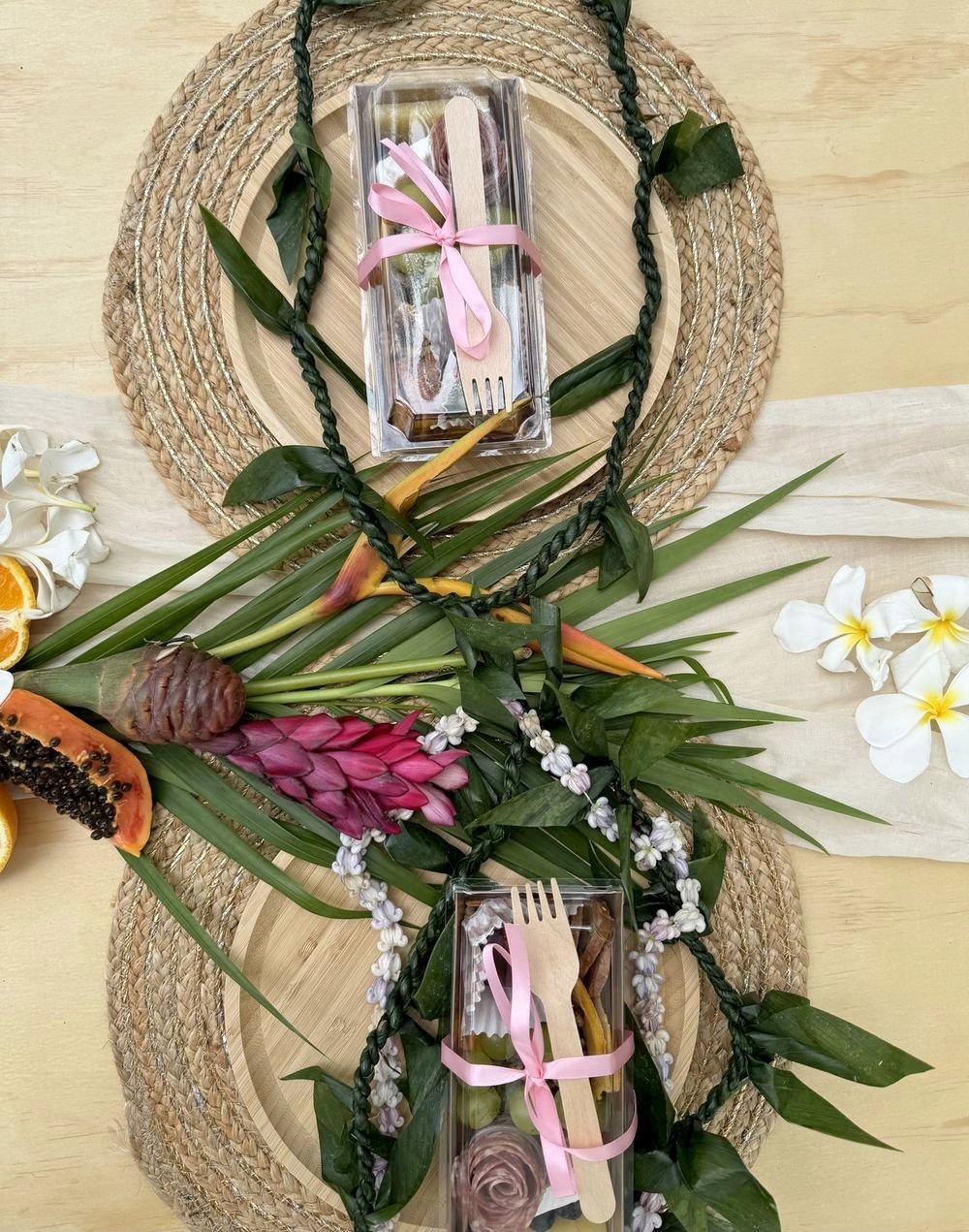 Top-down place settings with papaya, ginger and bird of paradise on a woven charger