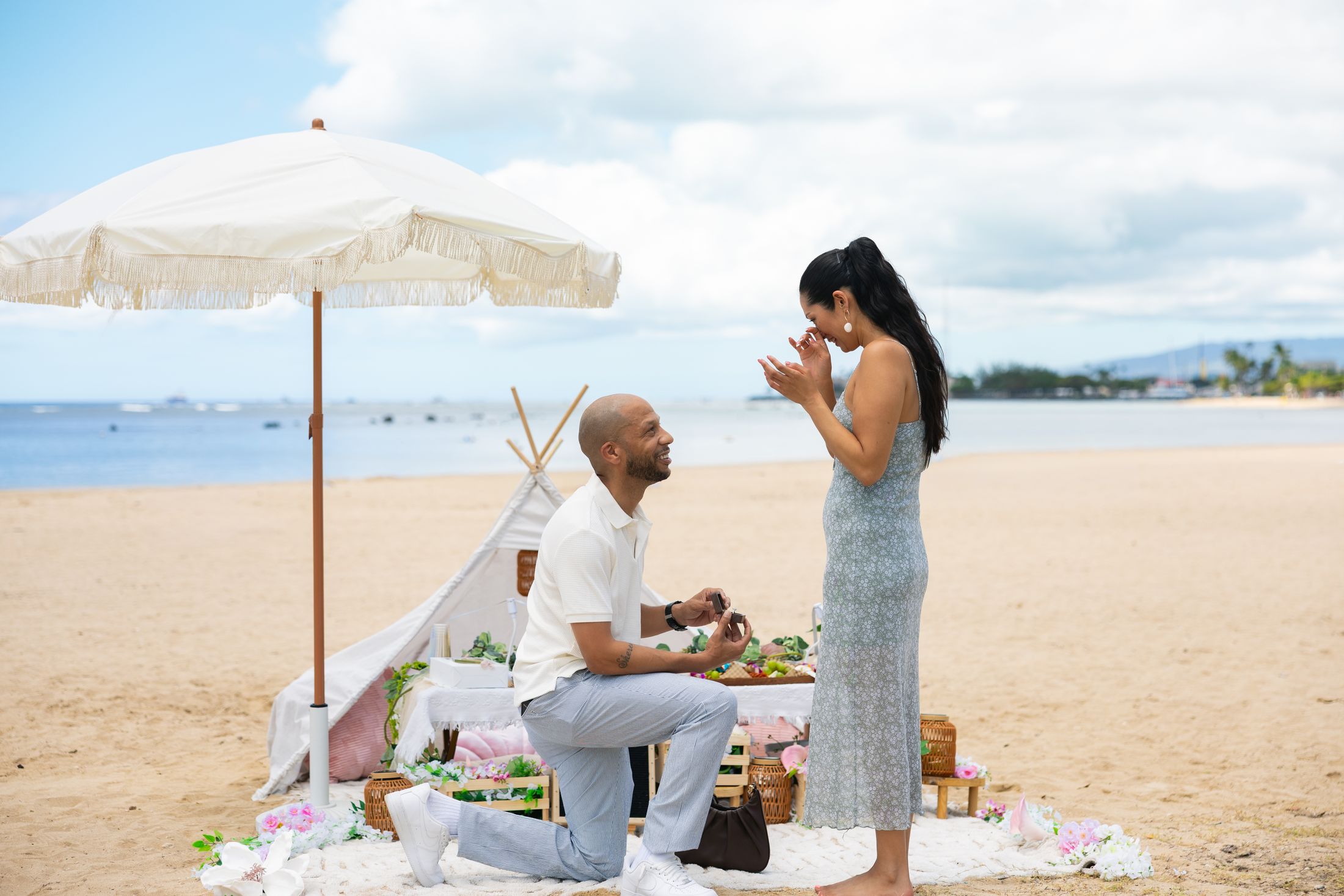 James proposes to Emily beside a styled teepee picnic on the beach