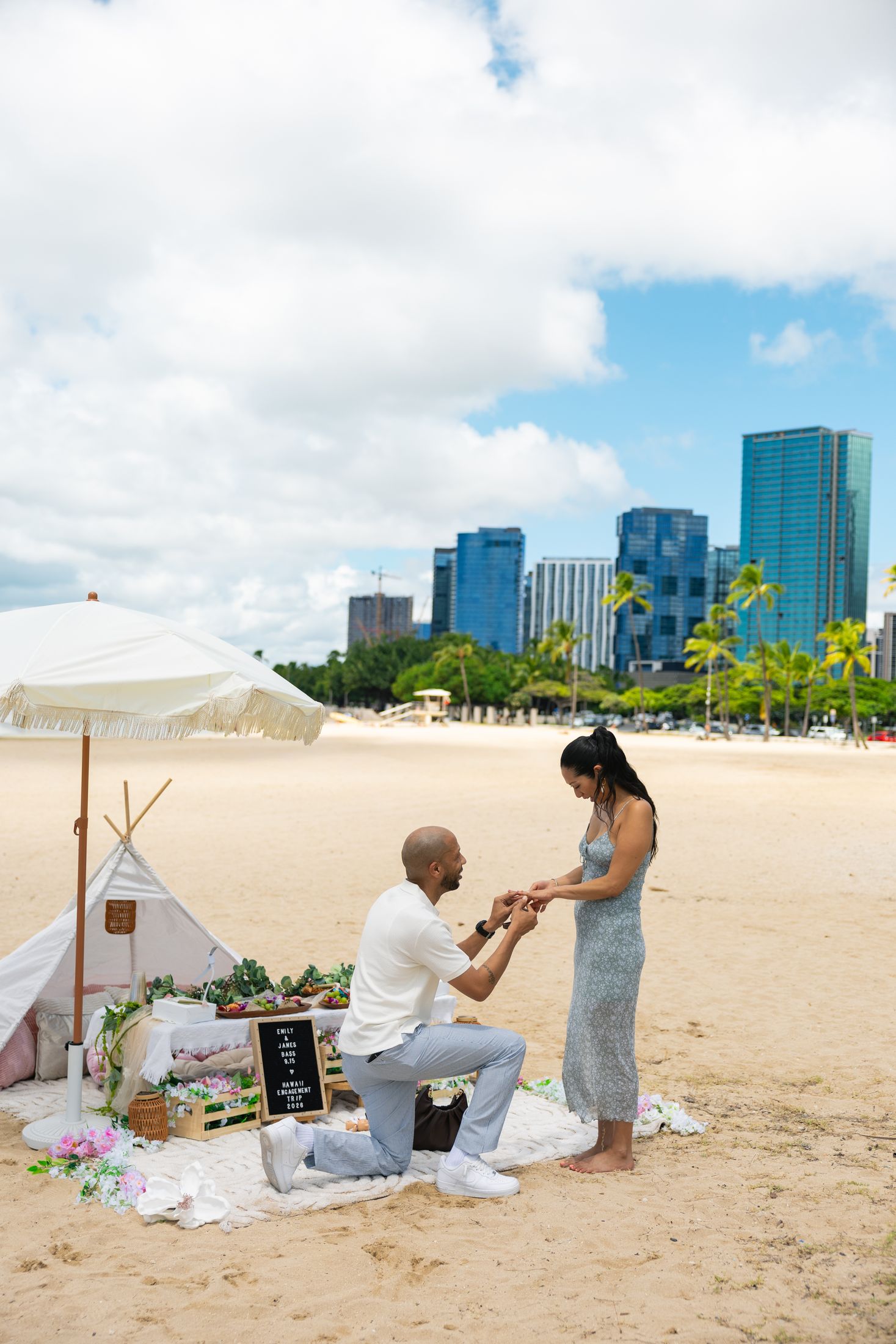 Proposal on the sand with the Honolulu skyline behind the teepee picnic