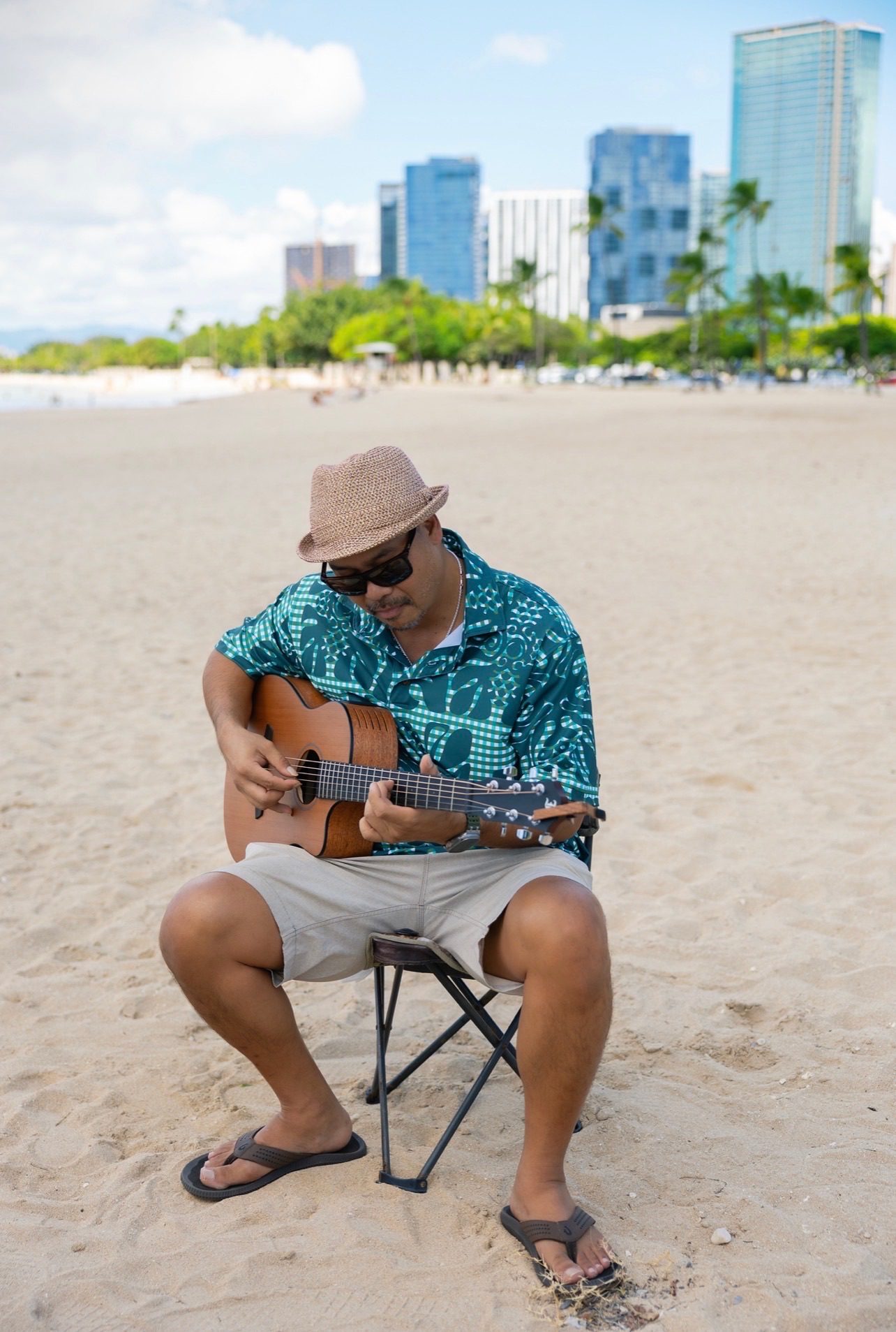 Live guitarist in an aloha shirt playing on the sand