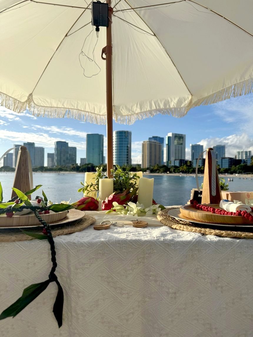 Fringed umbrella over a candlelit table with the Honolulu skyline across the water