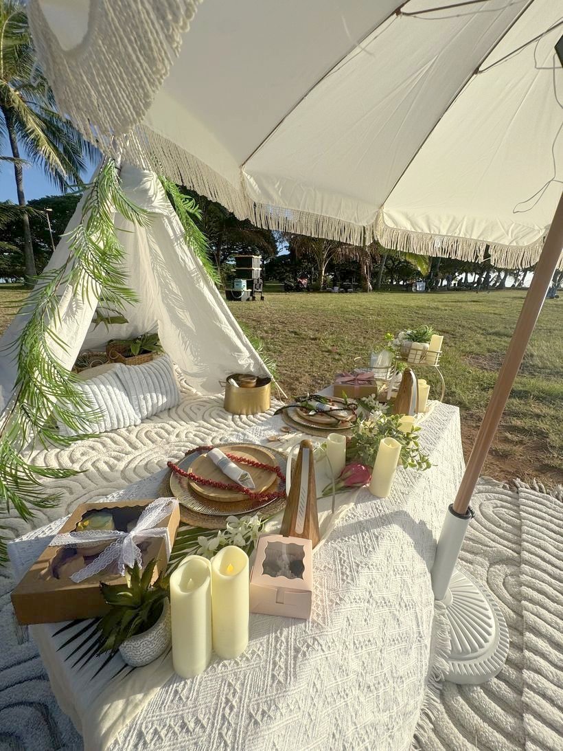 Teepee and fringed umbrella with candles on a lawn picnic